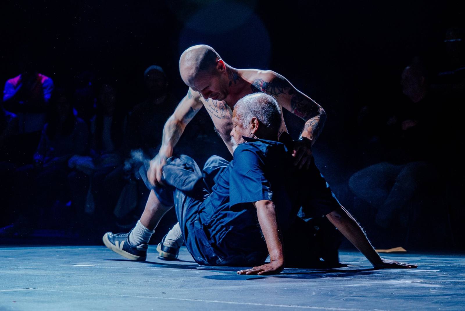 Retro-Active: Ishmael Houston-Jones sits on the floor in blue coveralls as a shirtless Dan Safer leans over his back