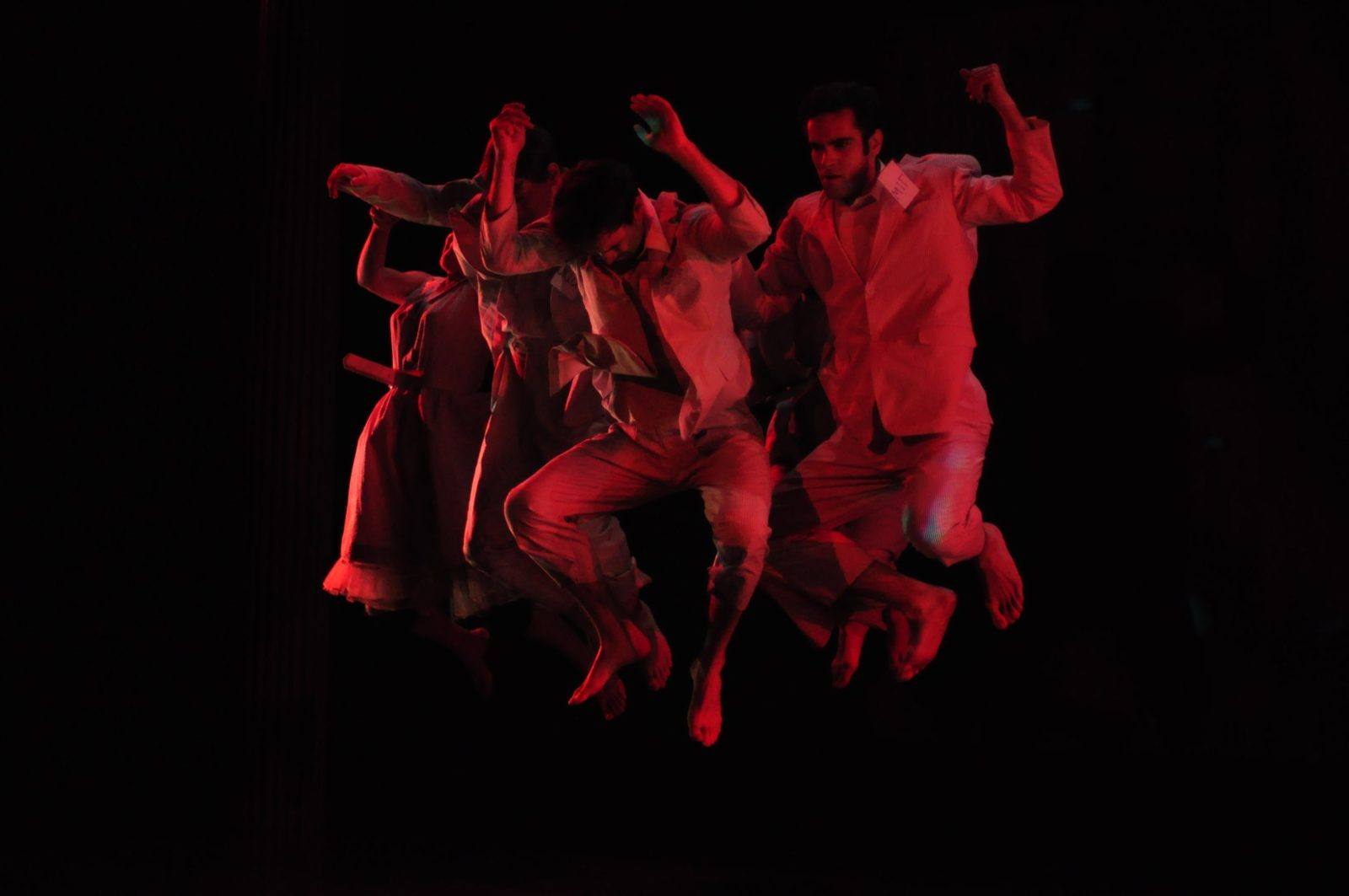 The Panic Show: dancers in white leap together in red light