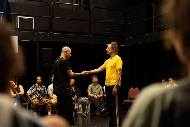 Dan Safer and Thomas F. DeFrantz clasp hands in the middle of the studio as the audience watches
