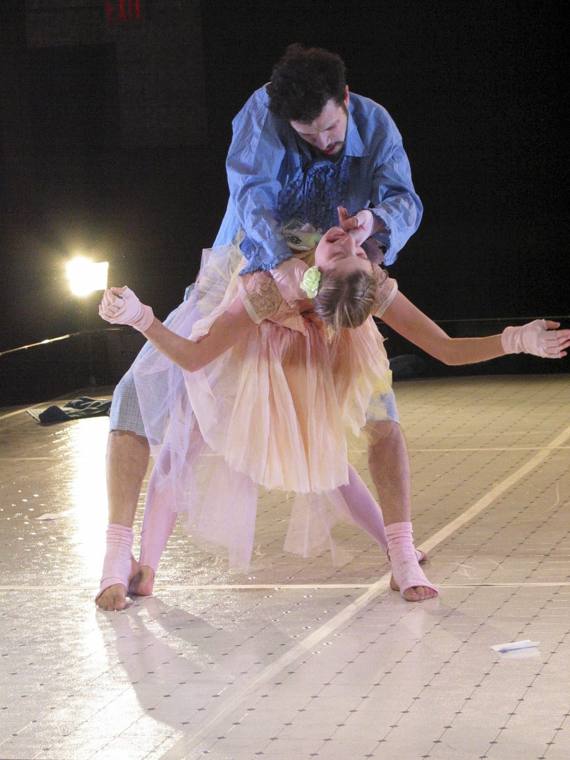 A man in a ruffled blue shirt dips a dancer in a peach tutu
